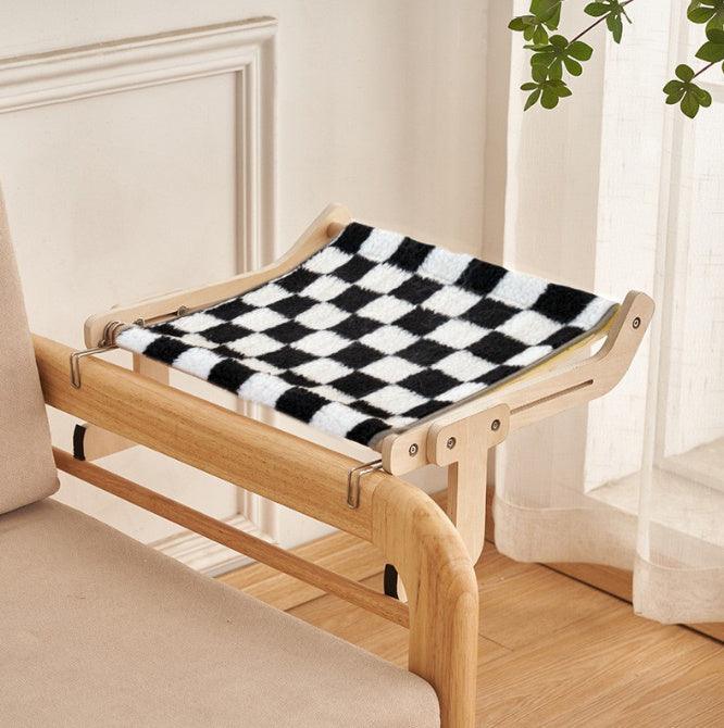 Chic cat hanging bed with a black and white plaid fabric and sturdy wooden frame, easily attachable to furniture for a stylish look.