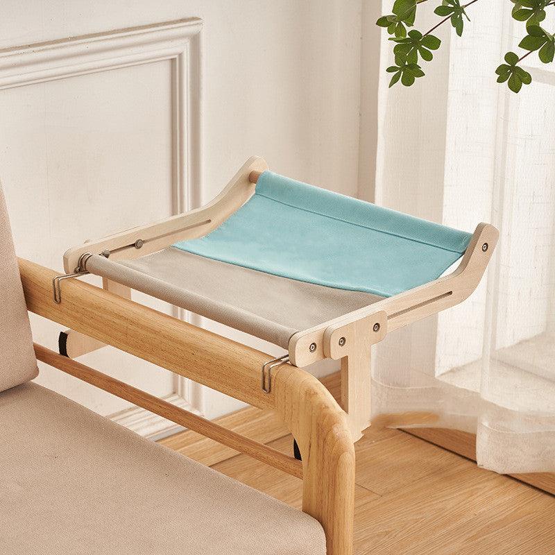 Compact cat hanging bed with a wooden frame and blue-gray fabric, designed for easy attachment to furniture. Ideal for small spaces.