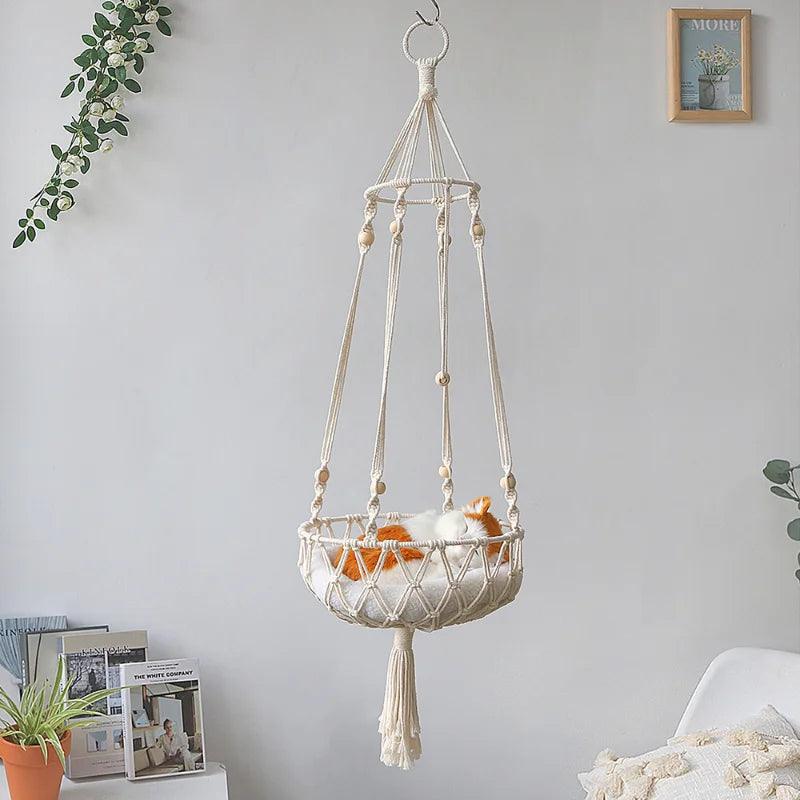 Macrame cat swing bed hanging in a modern living space, featuring a woven rope design and tassel fringe.